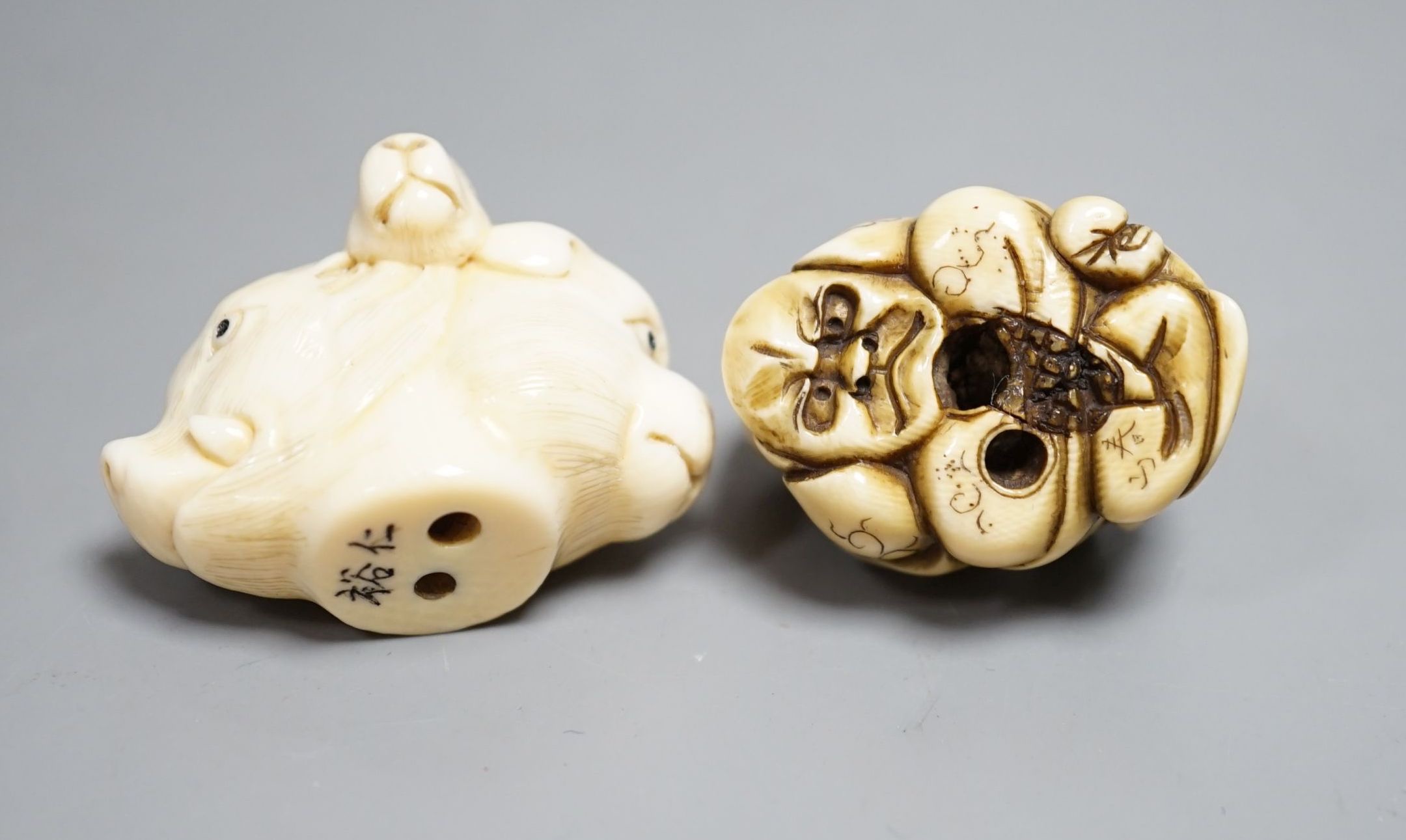 A Japanese ivory Netsuke of two boys holding a noh mask, an ivory Netsuke in the form of three animal heads and a coloured Ivory carving of tortoises on a lotus leaf, all singed (3) largest 12cm